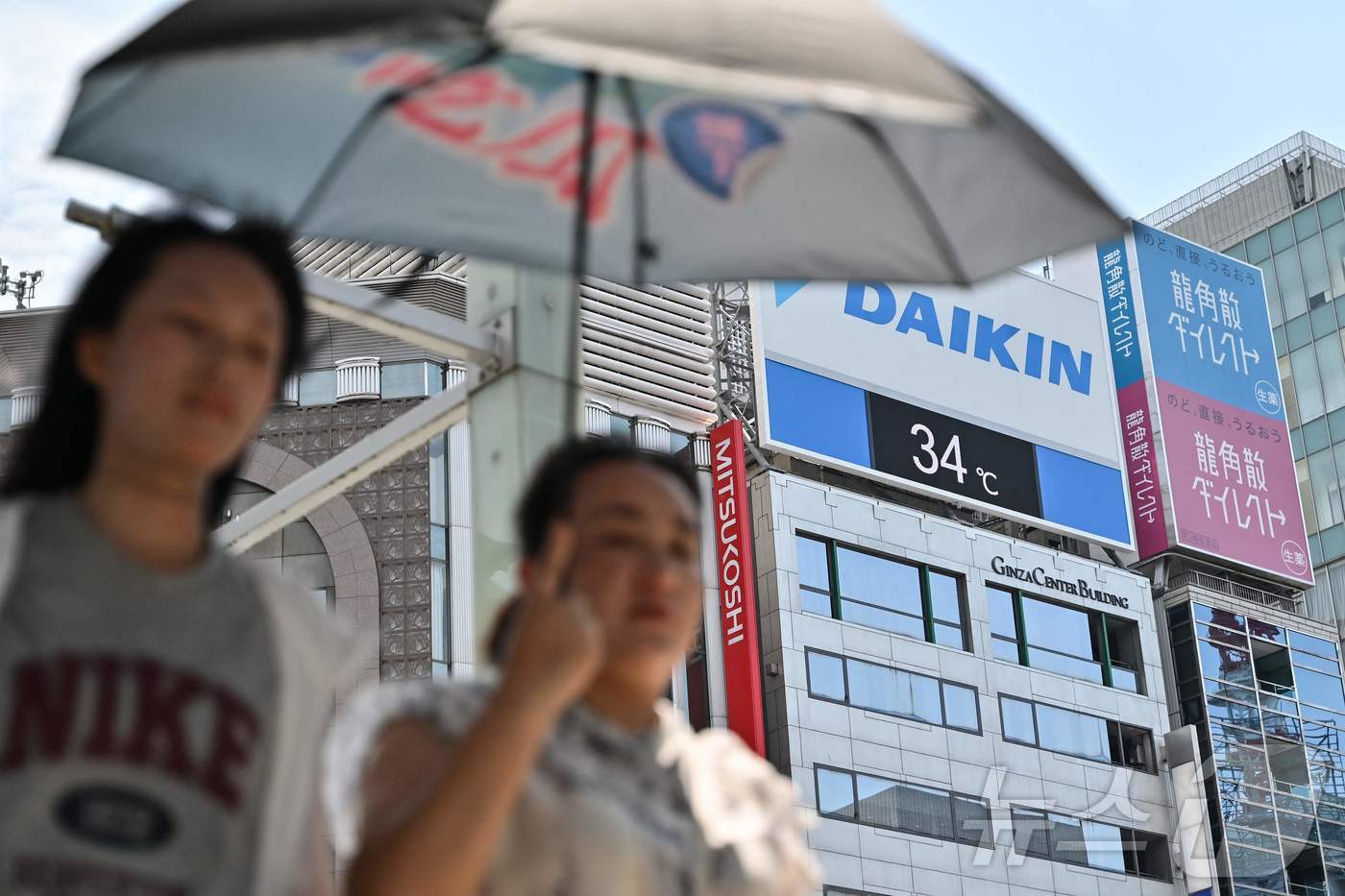 (도쿄 AFP=뉴스1) 김지완 기자 = 1일 양산을 쓴 시민들이 일본 도쿄 긴자 거리를 지나가고 있다. 시민들 뒤로 기온이 섭씨 34도로 표시된 전광판이 보인다. 2025.07.0 …