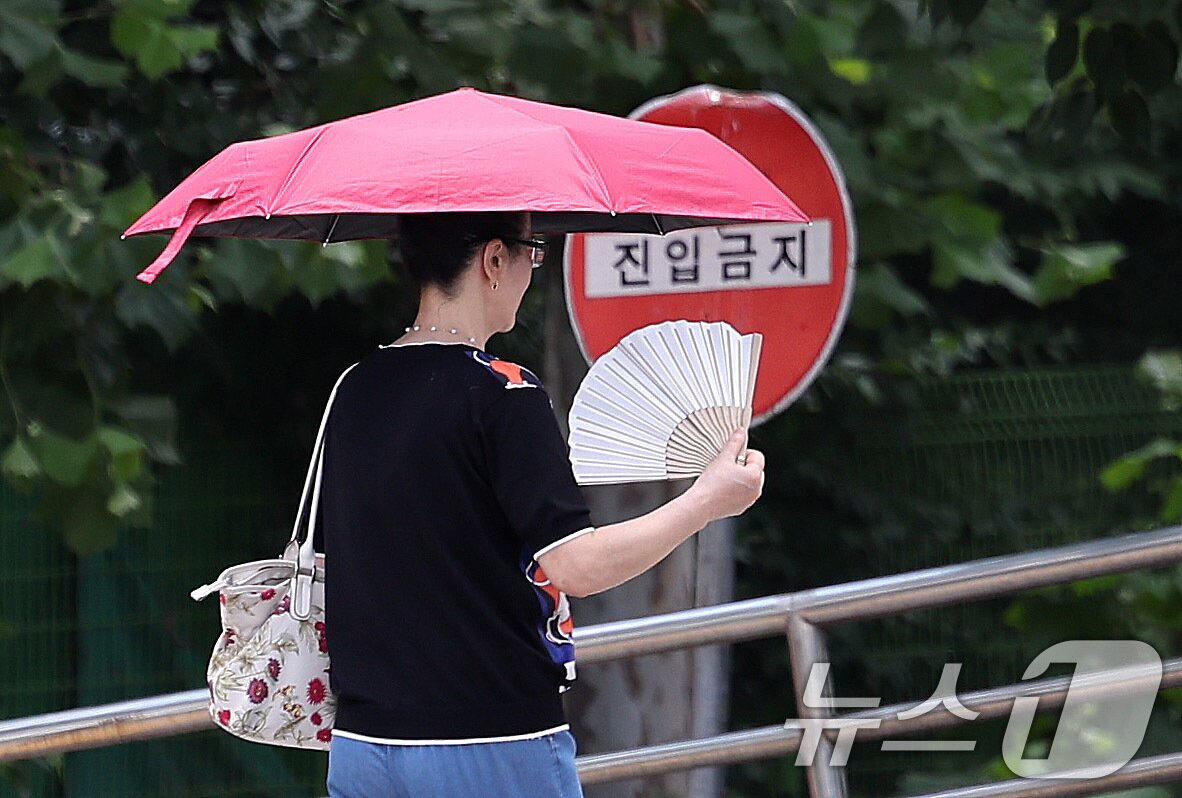 본문 이미지 - 무더위가 이어진 1일 서울 여의도에서 양산을 든 시민이 부채질을 하며 이동하고 있다. 2025.7.1/뉴스1 ⓒ News1 박지혜 기자