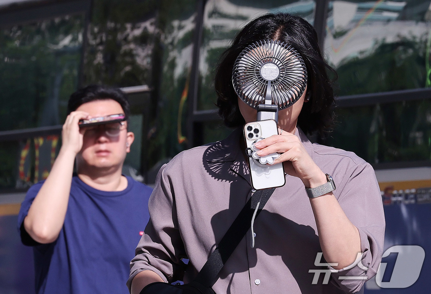 (서울=뉴스1) 박지혜 기자 = 폭염이 연일 이어지는 10일 서울 종로구 광화문광장 인근에서 한 시민이 손선풍기를 얼굴에 대며 출근하고 있다. 2025.7.10/뉴스1