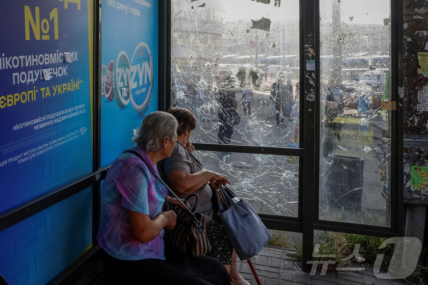 (키이우 로이터=뉴스1) 최종일 선임기자 = 10일(현지시간) 우크라이나 키이우에서 러시아의 드론 공격으로 유리창이 깨친 버스 정류장에 여성들이 앉아 있다. 2025.07.10ⓒ …