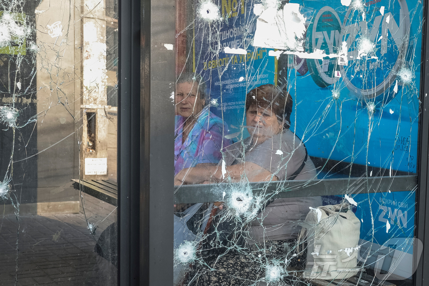 (키이우 로이터=뉴스1) 최종일 선임기자 = 10일(현지시간) 우크라이나 키이우에서 러시아의 드론 공격으로 유리창이 깨친 버스 정류장에 여성들이 앉아 있다. 2025.07.10ⓒ …