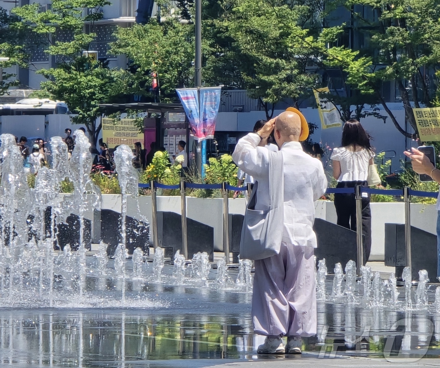 (서울=뉴스1) 황덕현 기후환경전문기자 = 11일 폭염 특보가 이어지는 서울 광화문에서 한 스님이 부채로 햇볕을 가리고 분수대를 바라보고 있다. 2025.7.11/뉴스1