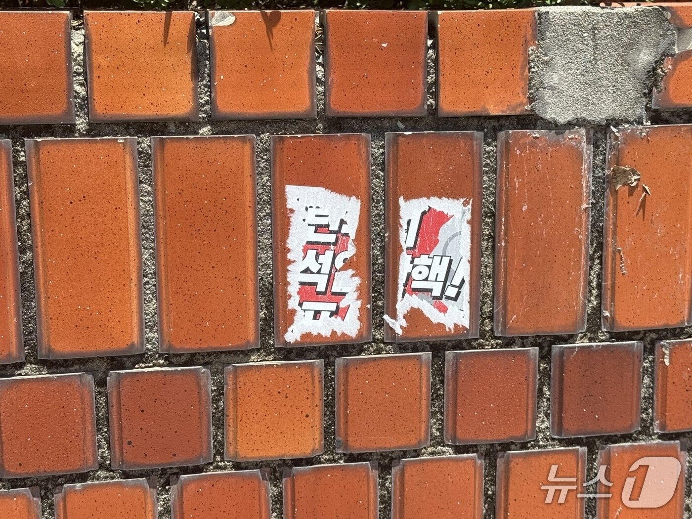 본문 이미지 - 서울 용산구 대통령 관저 인근 담벼락에 탄핵을 촉구하는 스티커가 완전히 제거되지 않은 채 남아 있다. 2025.7.11/뉴스1 ⓒ News1 김형준 기자