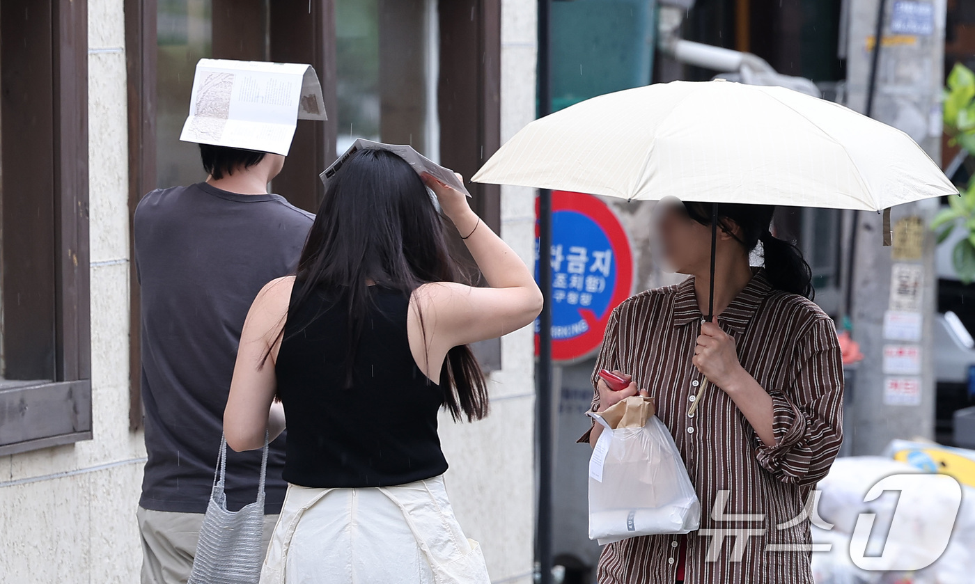 (서울=뉴스1) 김성진 기자 = 13일 서울 종로구 거리에서 시민들이 팜플렛으로 머리를 가린 채 거리를 거닐고 있다. 2025.7.13/뉴스1