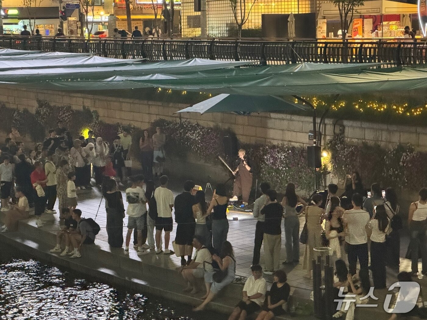 본문 이미지 - 11일 오후 청계천 모전교 일대에서 이뤄진 길거리 바이올린 공연을 외국인 관광객을 비롯한 수십 명의 시민들이 멈춰 서서 관람하고 있다. 2025.07.14/뉴스1 ⓒ 뉴스1 권준언 기자