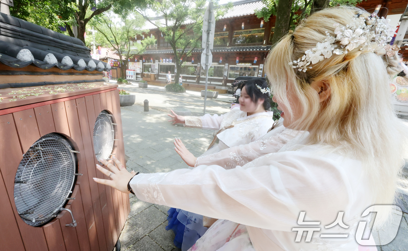 (전주=뉴스1) 유경석 기자 = 14일 전북 전주시 한옥마을 태조로에서 관광객들이 쿨링포그 앞에서 더위를 식히고 있다. 2025.7.14/뉴스1