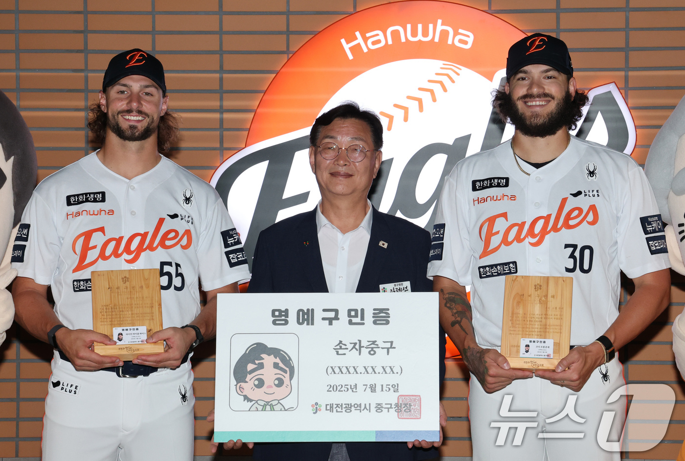 (대전=뉴스1) 김기태 기자 = 김재선 대전 중구청장이 15일 대전 한화생명 볼파크에서 한화이글스 외국인 투수 라이언 와이스(왼쪽)와 코디 폰세에게 명예구민증과 명예패를 전달한 뒤 …
