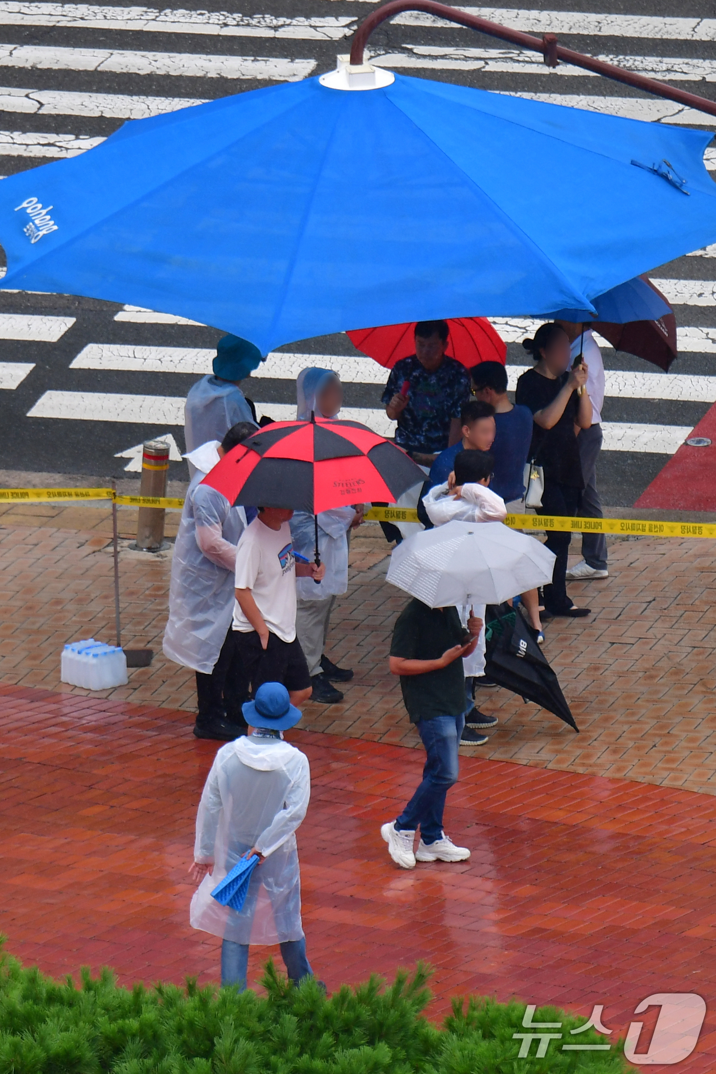 (포항=뉴스1) 최창호 기자 = 16일 오후 경북 포항시 전역에 비가 내리는 가운데 포항시청 횡단보도 앞에 설치된 대형 우산 그늘막 밑에서 시민들이 비를 피하고 있다.  2025. …