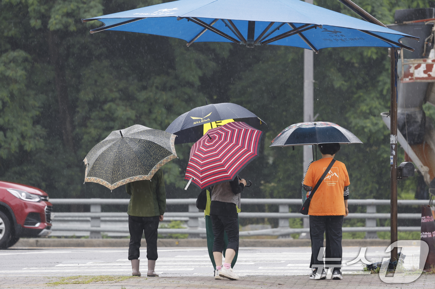 (광주=뉴스1) 김태성 기자 = 16일 오전 광주광역시 전역에 비가 내리는 가운데 광산구 수완지구 횡단보도 앞에 설치된 대형 우산 밑에 시민들이 우산을 쓰고 비를 피하고 있다. 2 …