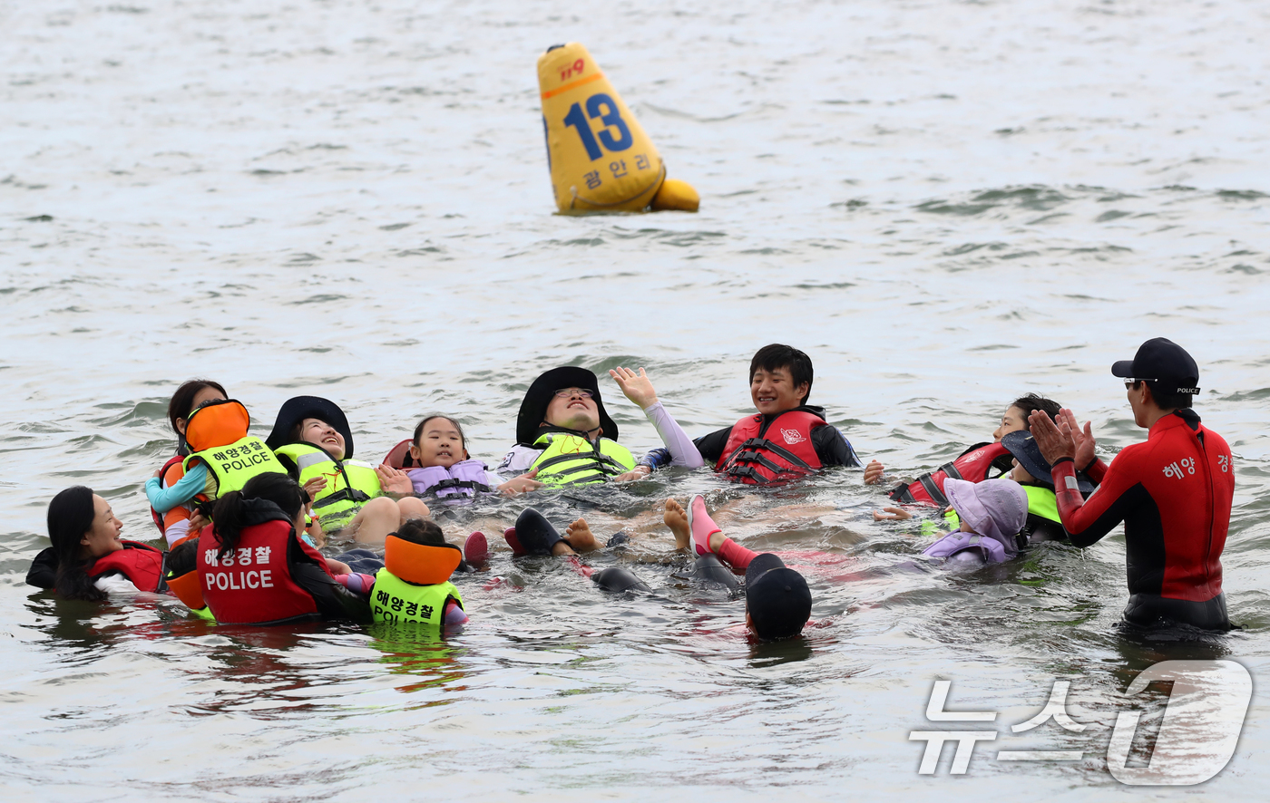 (부산=뉴스1) 윤일지 기자 = 16일 오후 부산 수영구 광안리해수욕장에서 열린 부산해양경찰서 생존수영 체험교실에서 참가자들이 해양경찰관에게 생존수영을 배우고 있다.  2025.7 …