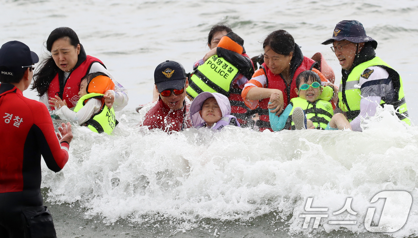 (부산=뉴스1) 윤일지 기자 = 16일 오후 부산 수영구 광안리해수욕장에서 열린 부산해양경찰서 생존수영 체험교실에서 참가자들이 해양경찰관에게 생존수영을 배우고 있다.  2025.7 …