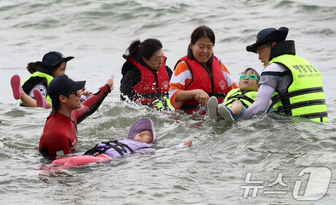 (부산=뉴스1) 윤일지 기자 = 16일 오후 부산 수영구 광안리해수욕장에서 열린 부산해양경찰서 생존수영 체험교실에서 참가자들이 해양경찰관에게 생존수영을 배우고 있다.  2025.7 …