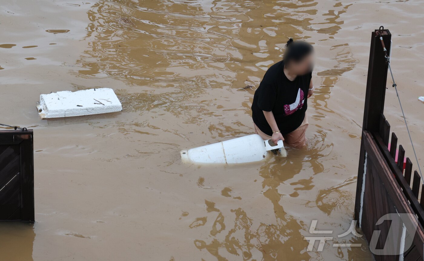 본문 이미지 - 밤 사이 쏟아진 집중폭우로 침수 피해가 발생한 17일 오전 충남 예산군 삽교읍에서 주택가 일부가 침수돼 주민이 떠내려간 가재도구를 옮기고 있다. 2025.7.17/뉴스1 ⓒ News1 김기태 기자