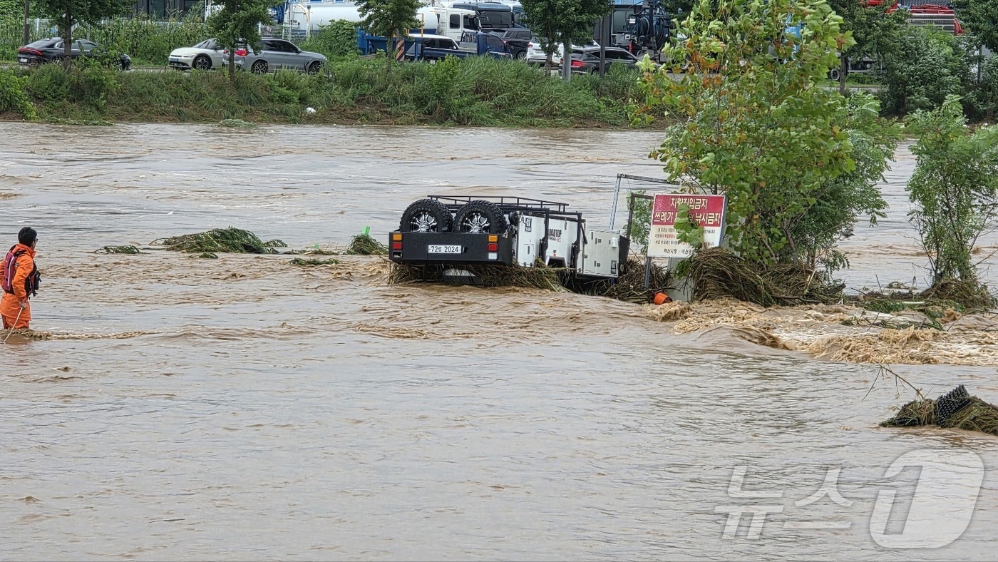 (아산=뉴스1) 이시우 기자 = 밤사이 쏟아진 집중폭우로 침수 피해가 발생한 17일 충남 아산시 배방읍 곡교천변에서 소방대원들이 불어난 빗물에 쓰러진 시설물과 침수차량을 살펴보고 …