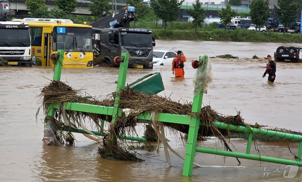 본문 이미지 - 밤사이 쏟아진 집중폭우로 침수 피해가 발생한 17일 충남 아산시 배방읍 곡교천변에서 소방대원들이 불어난 빗물에 쓰러진 시설물과 침수차량을 살펴보고 있다. 2025.7.17/뉴스1 ⓒ News1 이시우 기자