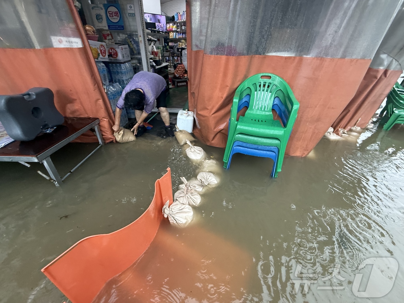 (광주=뉴스1) 김태성 기자 = 호우경보가 발효된 17일 광주 남구 백운동 일대의 상가가 침수돼 주인이 빗물을 쓸어내고 있다. 2025.7.17/뉴스1