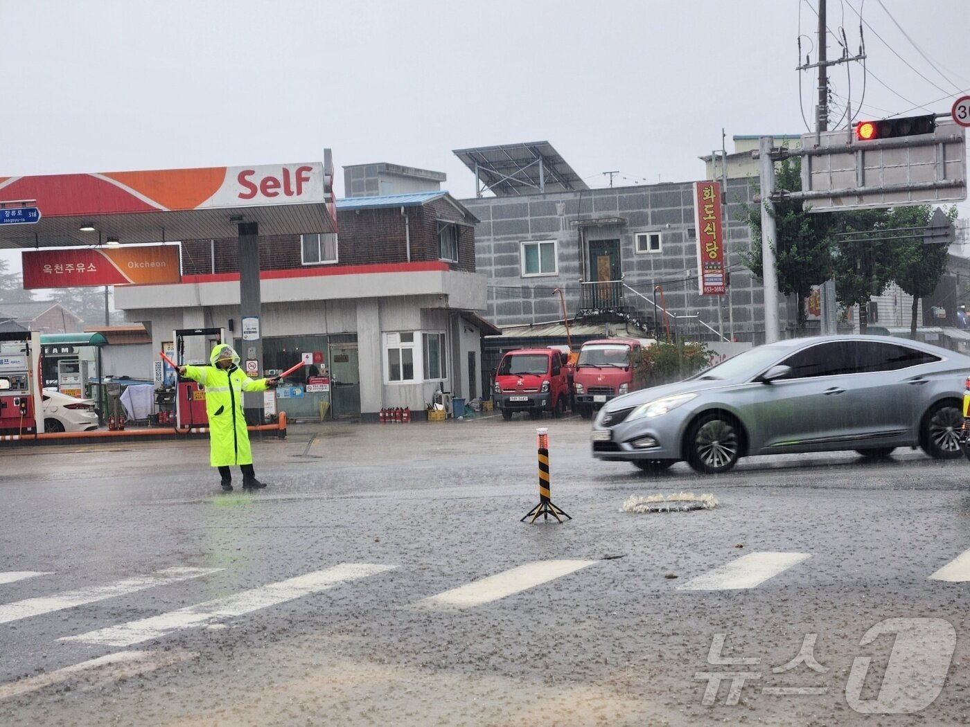 본문 이미지 - 17일 오후 전북 순창군 한 도로에 맨홀 뚜껑이 폭우에 역류해 한 경찰관이 현장에서 교통지도를 하고 있다. (전북경찰청 제공. 재판매 및 DB금지) 2025.7.17/뉴스1 ⓒ News1 장수인 기자