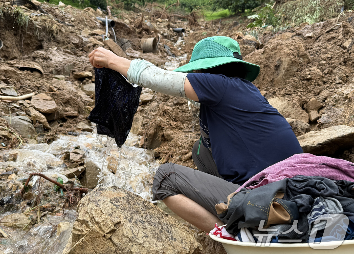 (청도=뉴스1) 공정식 기자 = 18일 경북 청도군 청도읍 구미리 주민이 전날 집중호우 때 쏟아진 토사에 파묻힌 옷가지를 씻고 있다. (독자 제공. 재판매 및 DB금지) 2025. …