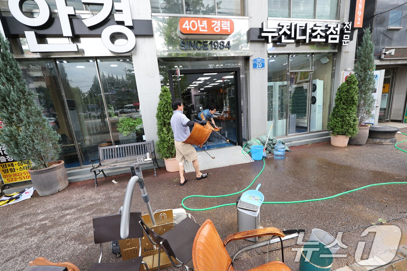 본문 이미지 - 18일 광주 북구 용봉동 전남대 후문 일대가 전날 내린 폭우로 침수돼 한 안경상가의 상인이 물에 젖은 의자를 닦은 후 옮기고 있다. 2025.7.18/뉴스1 ⓒ News1 박지현 기자