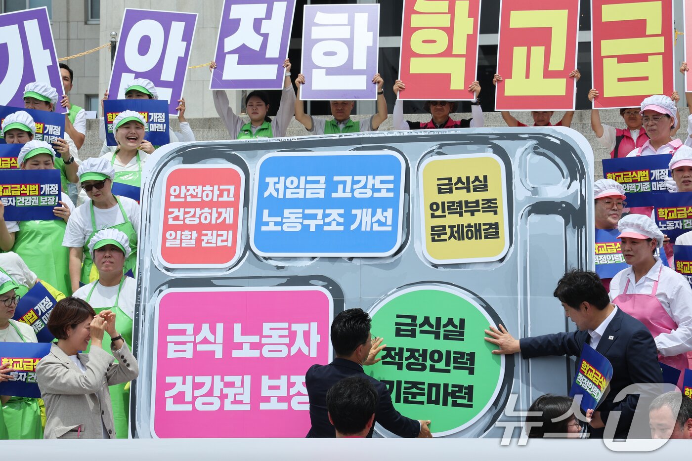 본문 이미지 - 2일 서울 여의도 국회 본청 계단에서 열린 '학교급식 노동자 건강과 안전 확보를 위한 학교급식법 개정안 발의 기자회견'에서 참석자들이 법안 국회 통과를 기원하며 식판 모양에 '안전하고 건강하게 일할 권리, 저임금 고강도 노동구조 개선, 급식실 인력부족 문제해결, 급식 노동자 건강권 보장, 급식실 적정인력 기준마련'이라고 적힌 메시지를 부착하고 있다. 2025.7.2/뉴스1 ⓒ News1 안은나 기자
