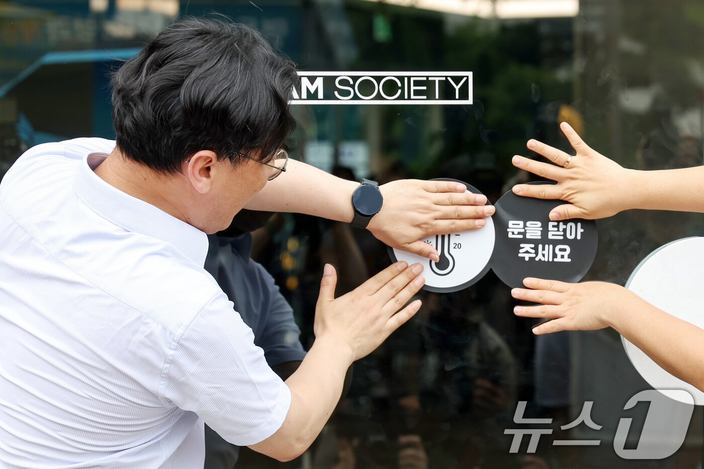 본문 이미지 - 이원주 산업통상자원부 대변인이 2일 오후 서울 중구 명동 온드림 소사이어티에서 열린 '여름철 에너지절약 캠페인'에 참석해 출입문에 개문냉방 자제 스티커를 붙이고 있다. 2025.7.2/뉴스1 ⓒ News1 민경석 기자