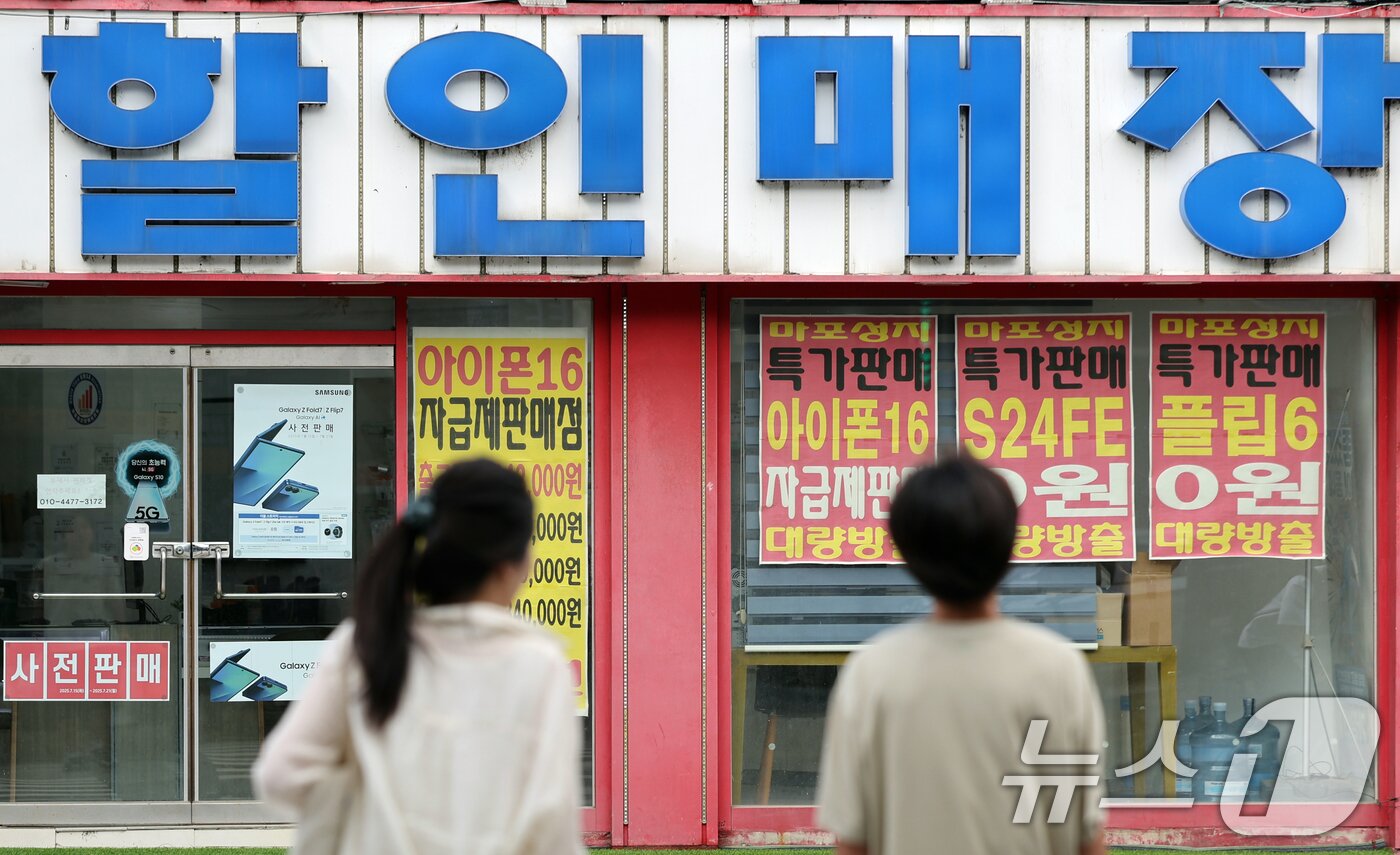 본문 이미지 - 서울 시내 한 핸드폰 매장앞에서 시민들이 이동하고 있다. 2025.7.20/뉴스1 ⓒ News1 황기선 기자