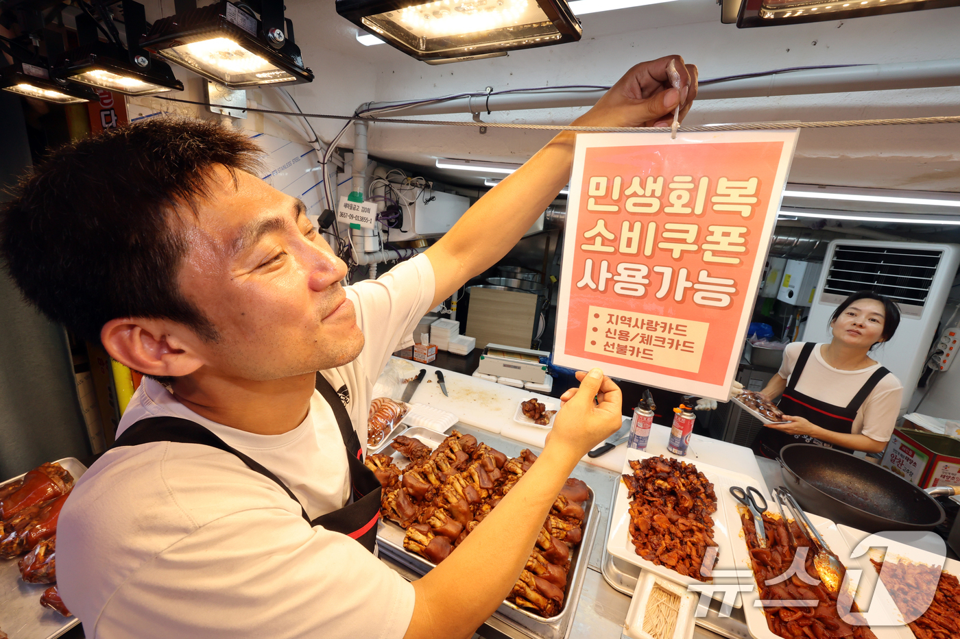 (서울=뉴스1) 황기선 기자 = 민생회복 소비쿠폰 1차 신청 첫 날인 21일 서울의 한 족발전문점에서 상인이 쿠폰 사용 관련 안내문을 붙이고 있다. 2025.7.21/뉴스1
