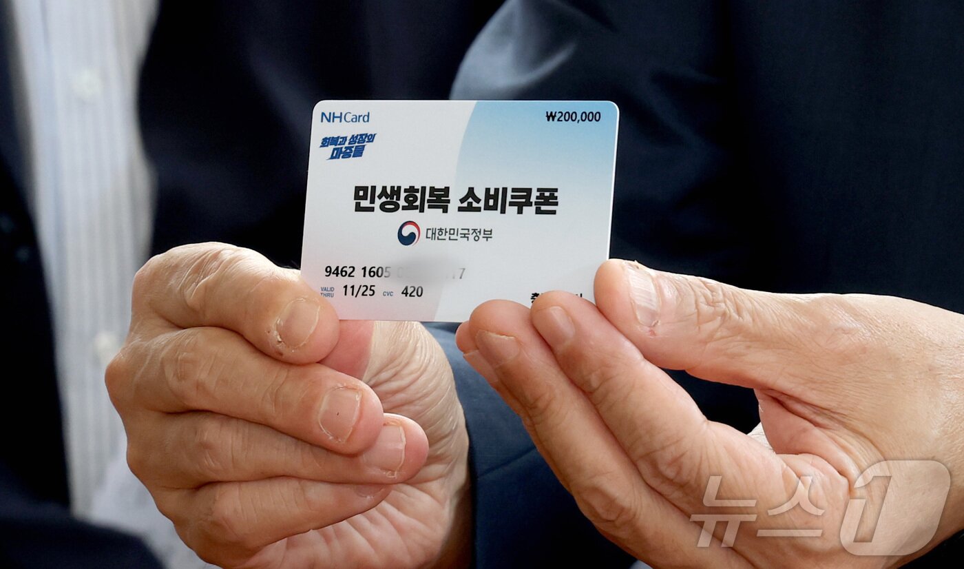 본문 이미지 - 구윤철 경제부총리 겸 기획재정부 장관이 21일 오후 민생회복 소비쿠폰 시행 첫날 충남 공주시 산성시장을 방문 과일가게등 재래시장 소비쿠폰 사용을 점검하며 소비쿠폰으로 과일을 구매하러 나온 시민의 카드를 들어 보이고 있다. 2025.7.21/뉴스1 ⓒ News1 김기남 기자