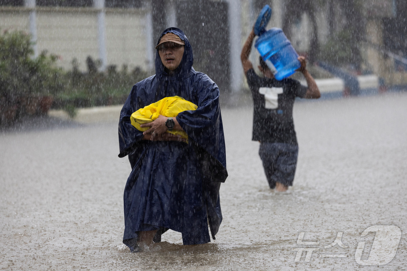 (카인타 로이터=뉴스1) 권영미 기자 = 22일 필리핀 리잘주의 카인타에서 몬순 우기로 인해 침수된 지역을 주민들이 걸어서 지나가고 있다. 2025.07.22.ⓒ 로이터=뉴스1