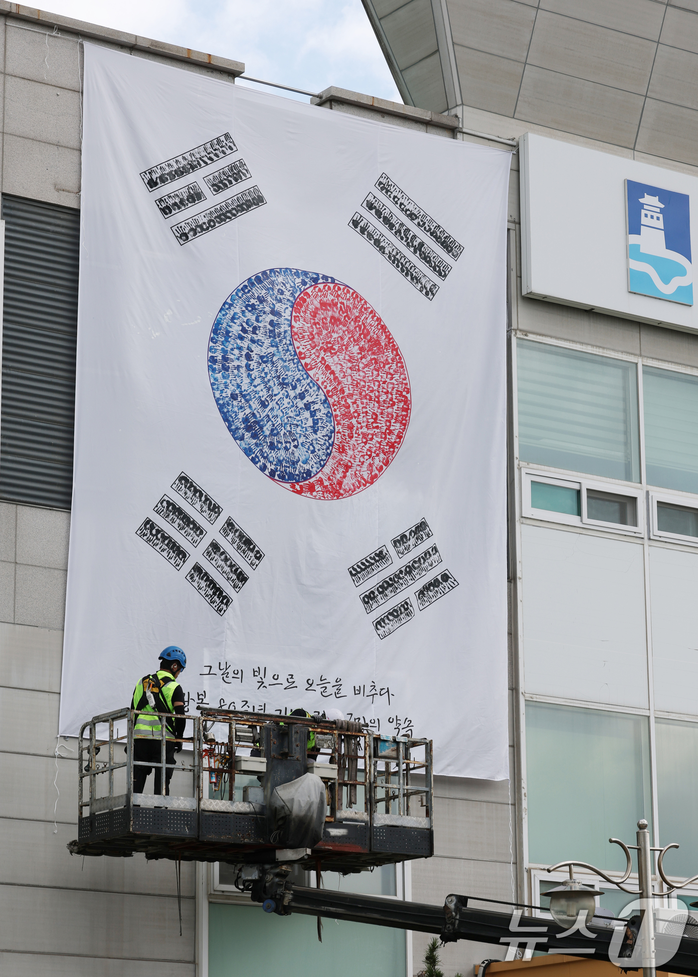 (수원=뉴스1) 김영운 기자 = 제80주년 광복절을 앞둔 22일 경기 수원시 권선구청 외벽에 손도장으로 만든 대형 태극기가 설치되고 있다. 2025.7.22/뉴스1