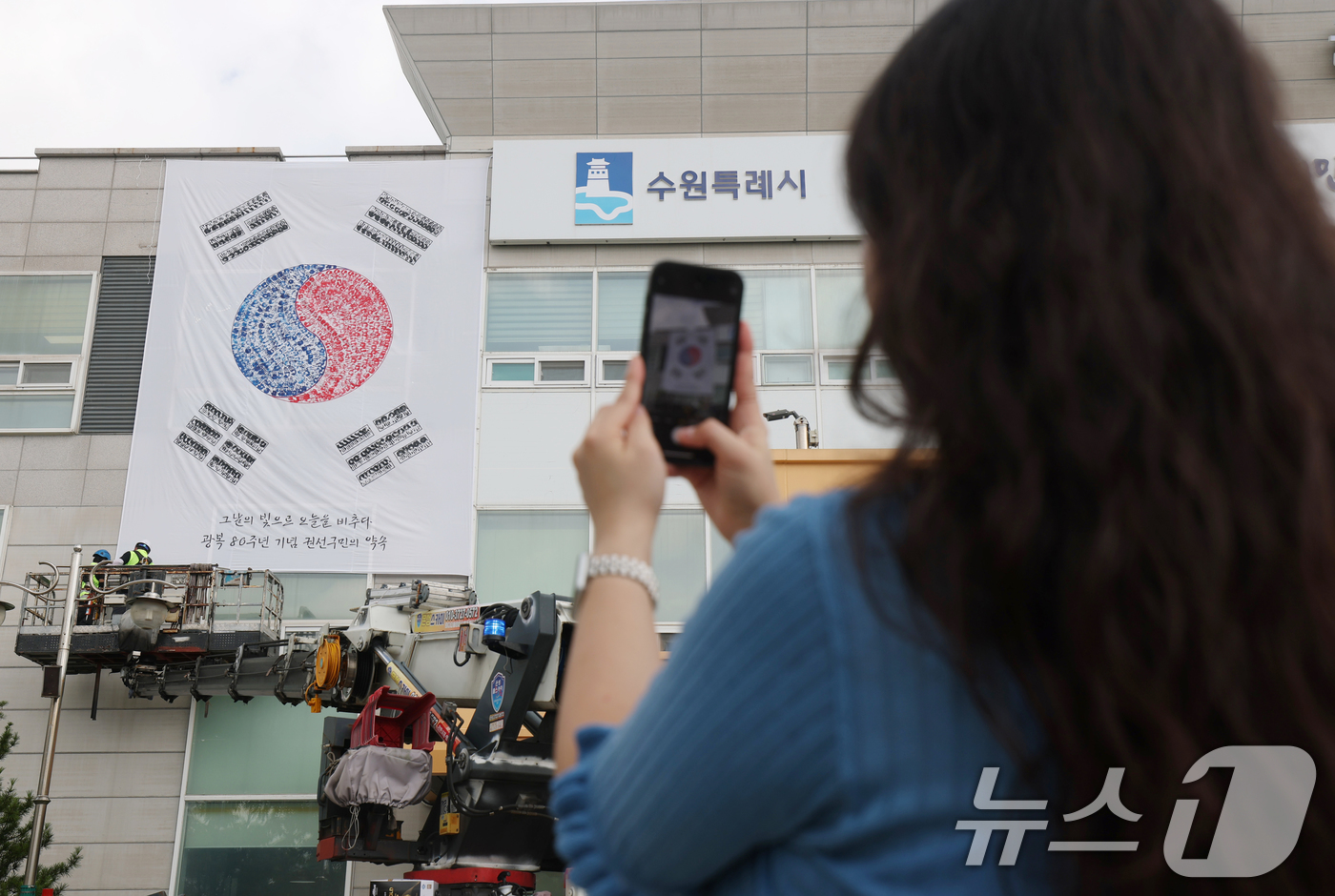 (수원=뉴스1) 김영운 기자 = 제80주년 광복절을 앞둔 22일 경기 수원시 권선구청 외벽에 손도장으로 만든 대형 태극기가 설치되고 있다. 2025.7.22/뉴스1