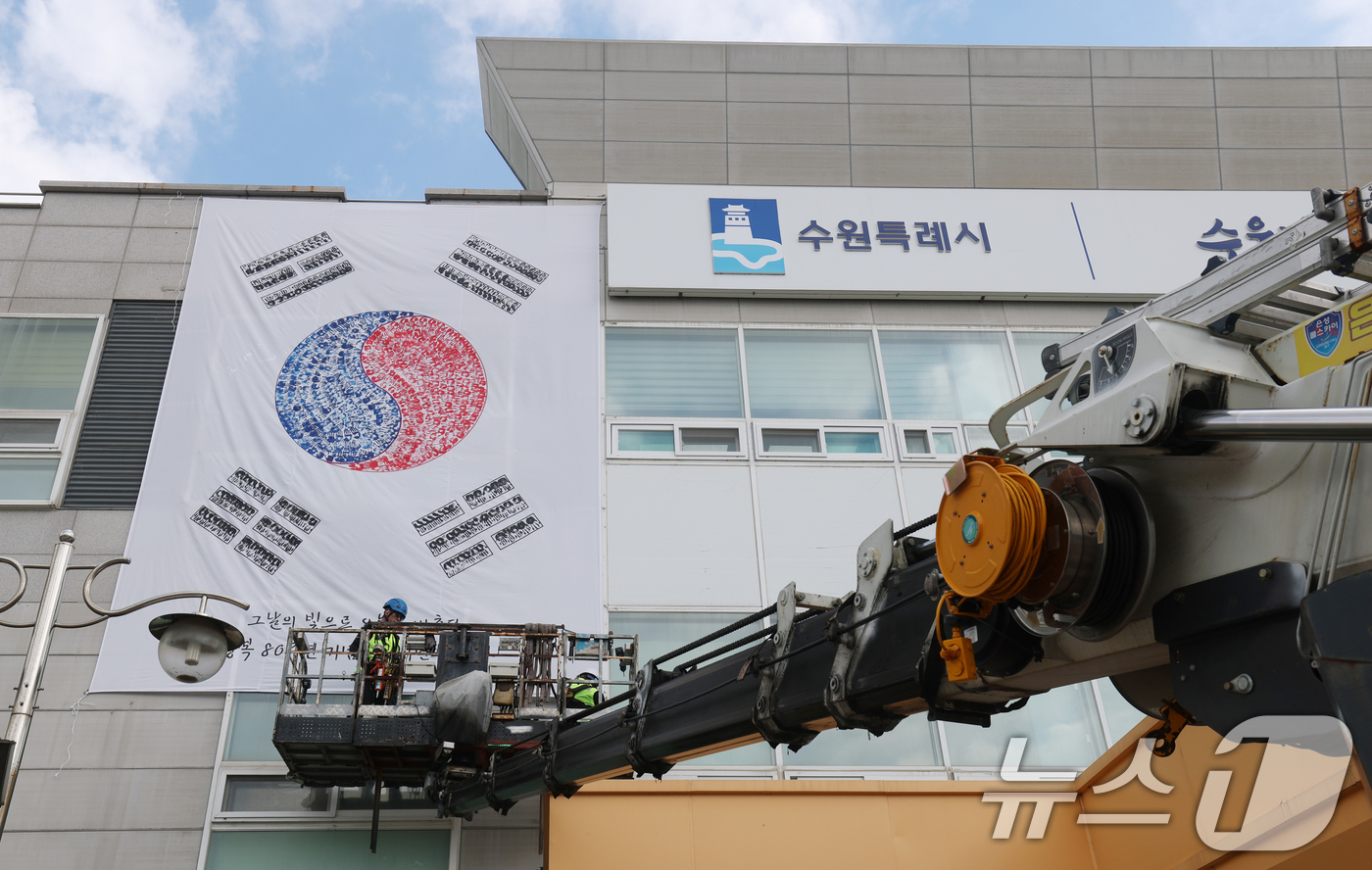 (수원=뉴스1) 김영운 기자 = 제80주년 광복절을 앞둔 22일 경기 수원시 권선구청 외벽에 손도장으로 만든 대형 태극기가 설치되고 있다. 2025.7.22/뉴스1