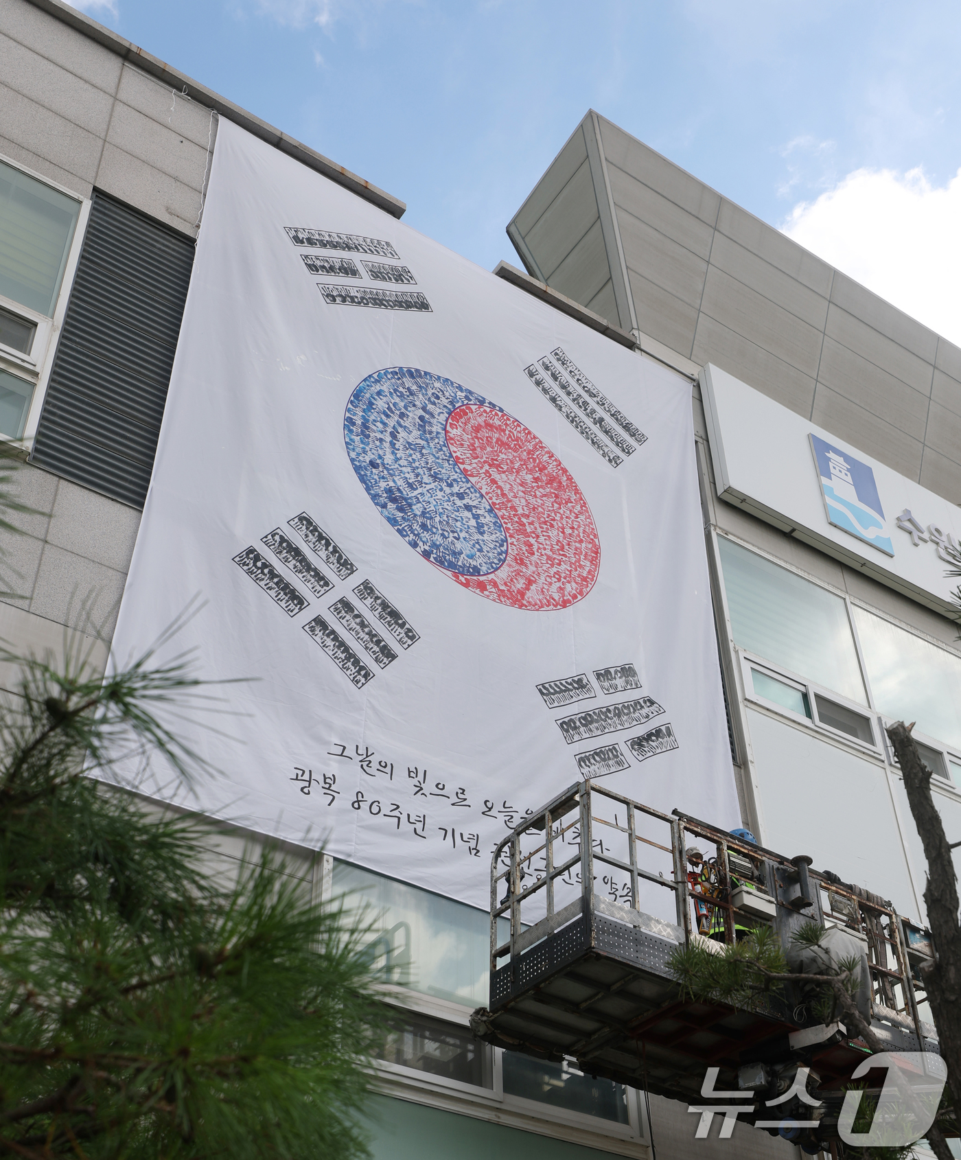 (수원=뉴스1) 김영운 기자 = 제80주년 광복절을 앞둔 22일 경기 수원시 권선구청 외벽에 손도장으로 만든 대형 태극기가 설치되고 있다. 2025.7.22/뉴스1