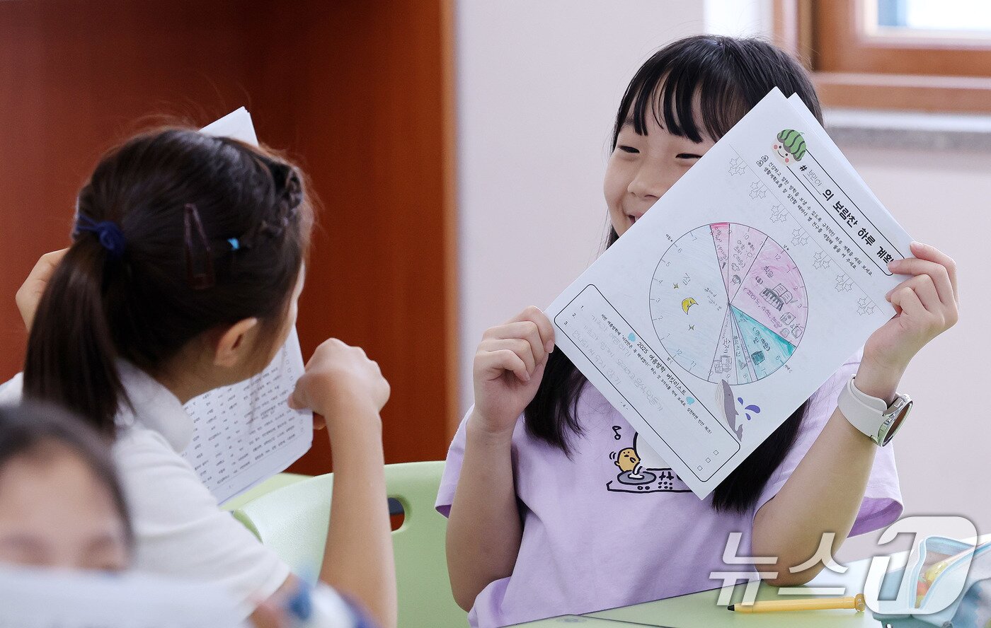 본문 이미지 - 23일 서울 동작구 삼일초등학교에서 열린 여름 방학식에서 학생들이 여름방학 계획표를 들어보이며 기뻐하고 있다. 2025.7.23/뉴스1 ⓒ News1 박지혜 기자