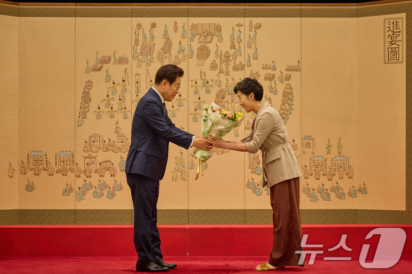 (서울=뉴스1) 허경 기자 = 이재명 대통령이 23일 서울 용산 대통령실 청사에서 열린 임명장 및 위촉장 수여식에서 김경수 지방시대위원장 배우자에게 꽃다발을 건네고 있다. (대통령 …