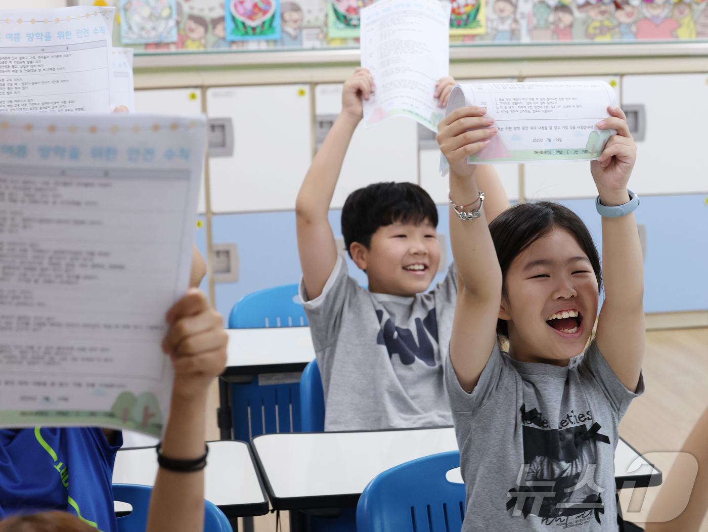 (수원=뉴스1) 김영운 기자 = 24일 경기 수원시 팔달구 매산초등학교에서 열린 여름 방학식에서 학생들이 가정통신문을 들어보이며 기뻐하고 있다.