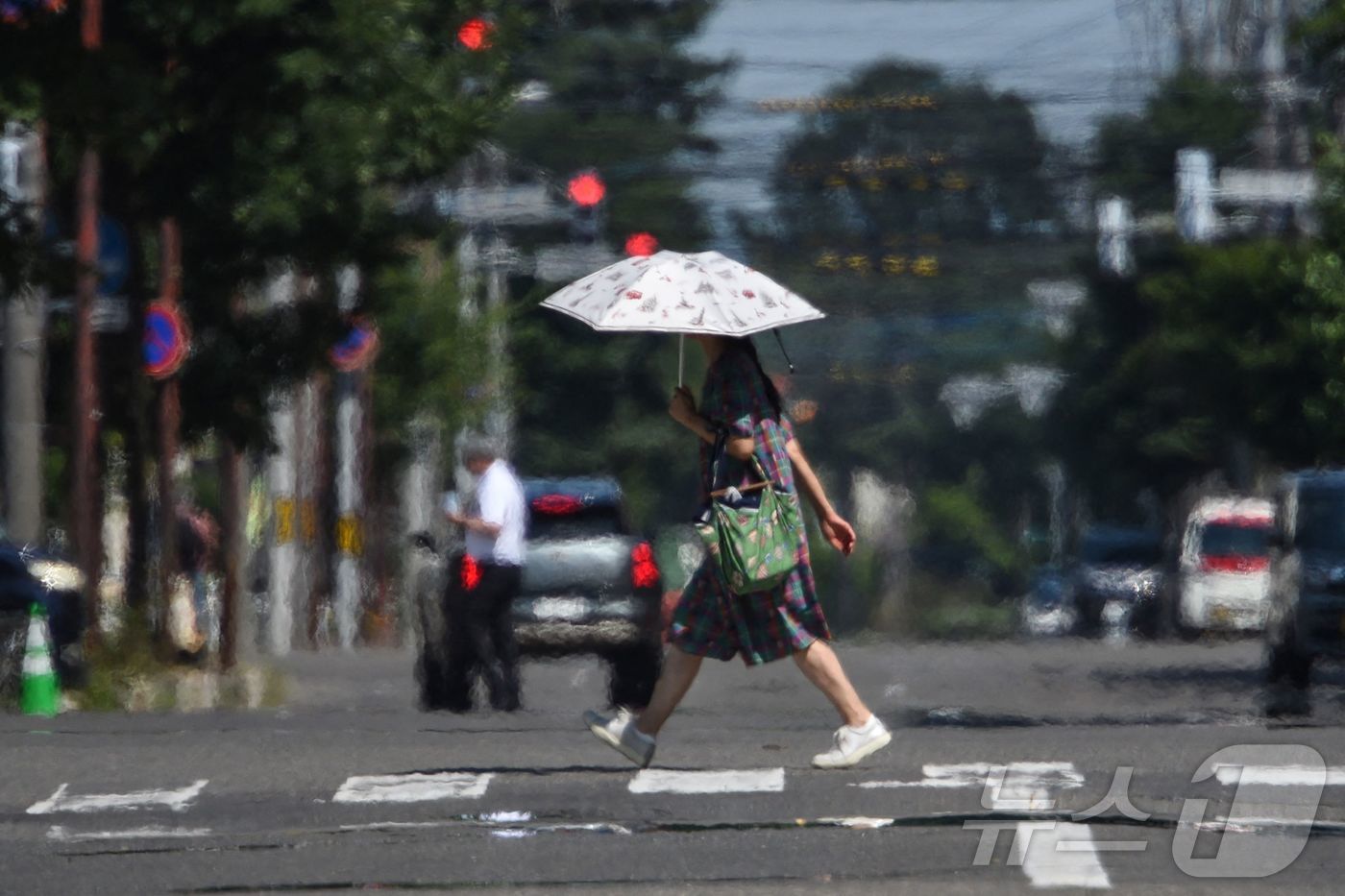 (오비히로 AFP=뉴스1) 강민경 기자 = 24일 폭염이 찾아온 일본 홋카이도 오비히로에서 한 행인이 양산을 쓰고 횡단보도를 건너고 있다. 2025.7.24ⓒ AFP=뉴스1