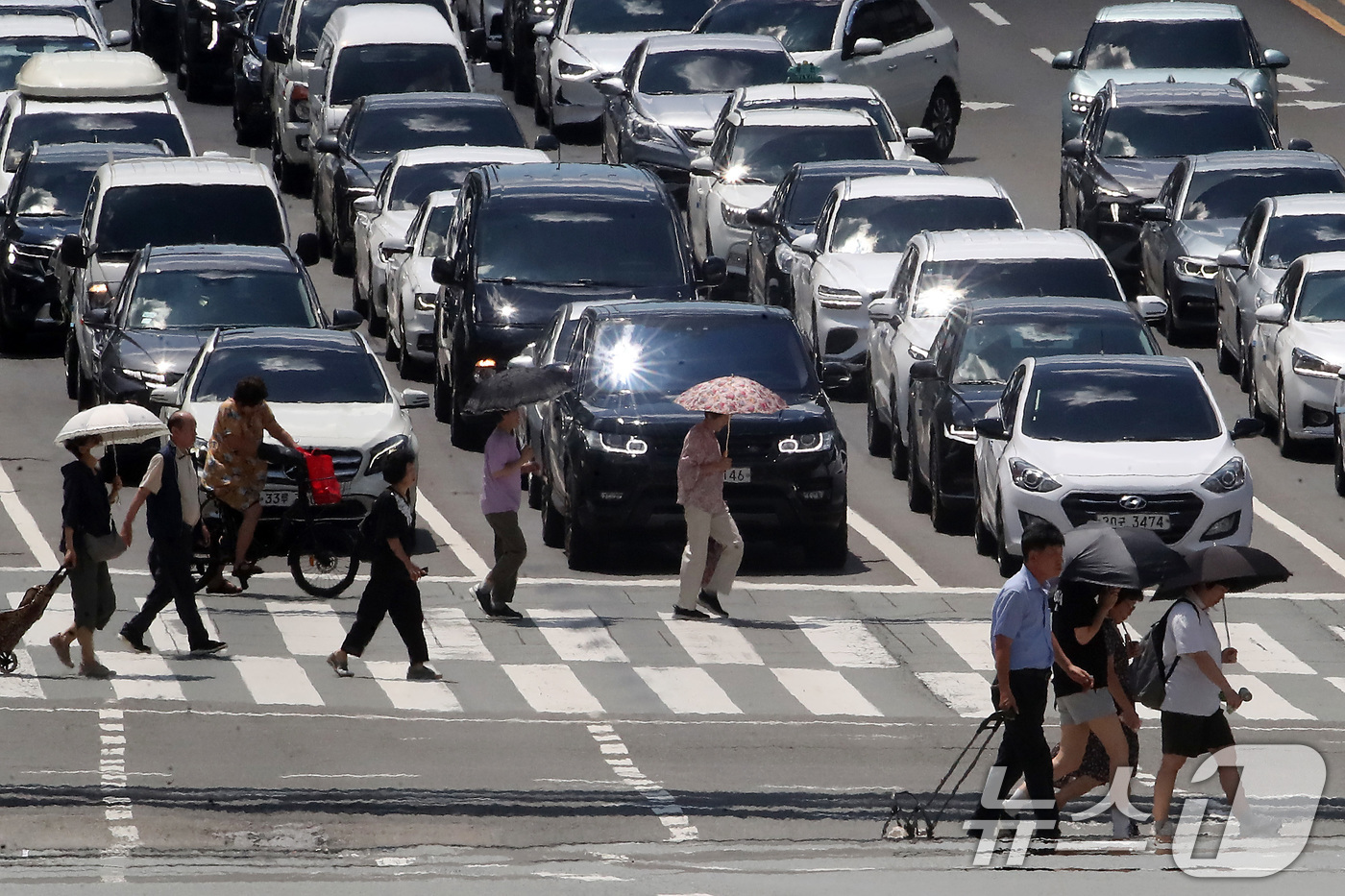 (대구=뉴스1) 공정식 기자 = 폭염이 연일 계속되는 25일 오후 대구 중구 달구벌대로에서 양산을 쓴 시민들이 아지랑이가 피어오르는 도로를 건너고 있다. 2025.7.25/뉴스1