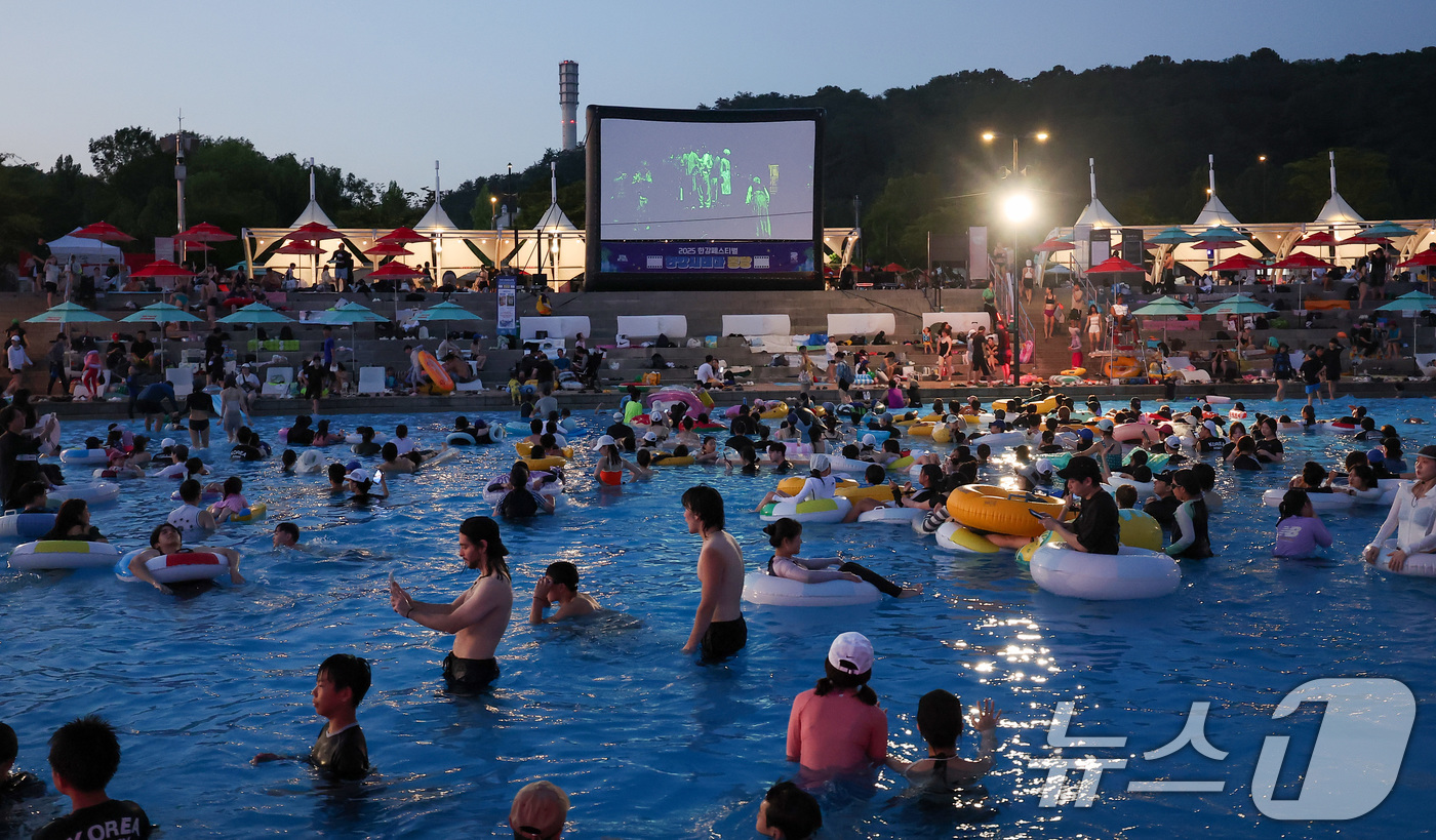 (서울=뉴스1) 김성진 기자 = 전국 대부분 지역에서 열대야가 나타난 27일 서울 마포구 난지한강 물놀이장에서 열린 '2025 한강페스티벌 여름' 한강시네마 퐁당을 찾은 시민들이 …