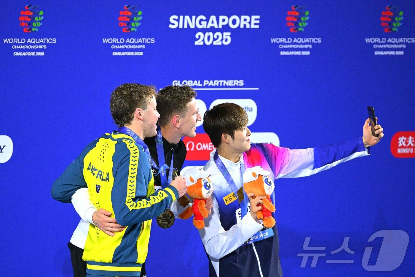 본문 이미지 - 김민(오른쪽)이 27일 열린 2025 싱가포르 세계수영선수권대회 남자 자유형 400m 결선에서 3분42초60의 기록으로 동메달을 획득했다. 시상대에 오른 김우민이 루카스 메르텐스(가운데), 새무얼 쇼트(왼쪽)와 함께 기념사진을 촬영하고 있다다. ⓒ AFP=뉴스1