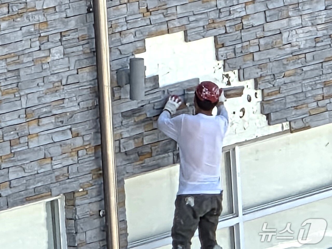 본문 이미지 - 한 건설 근로자가 석재타일이 떨어져 나간 보은군의회 청사 외벽을 보수하고 있다.  