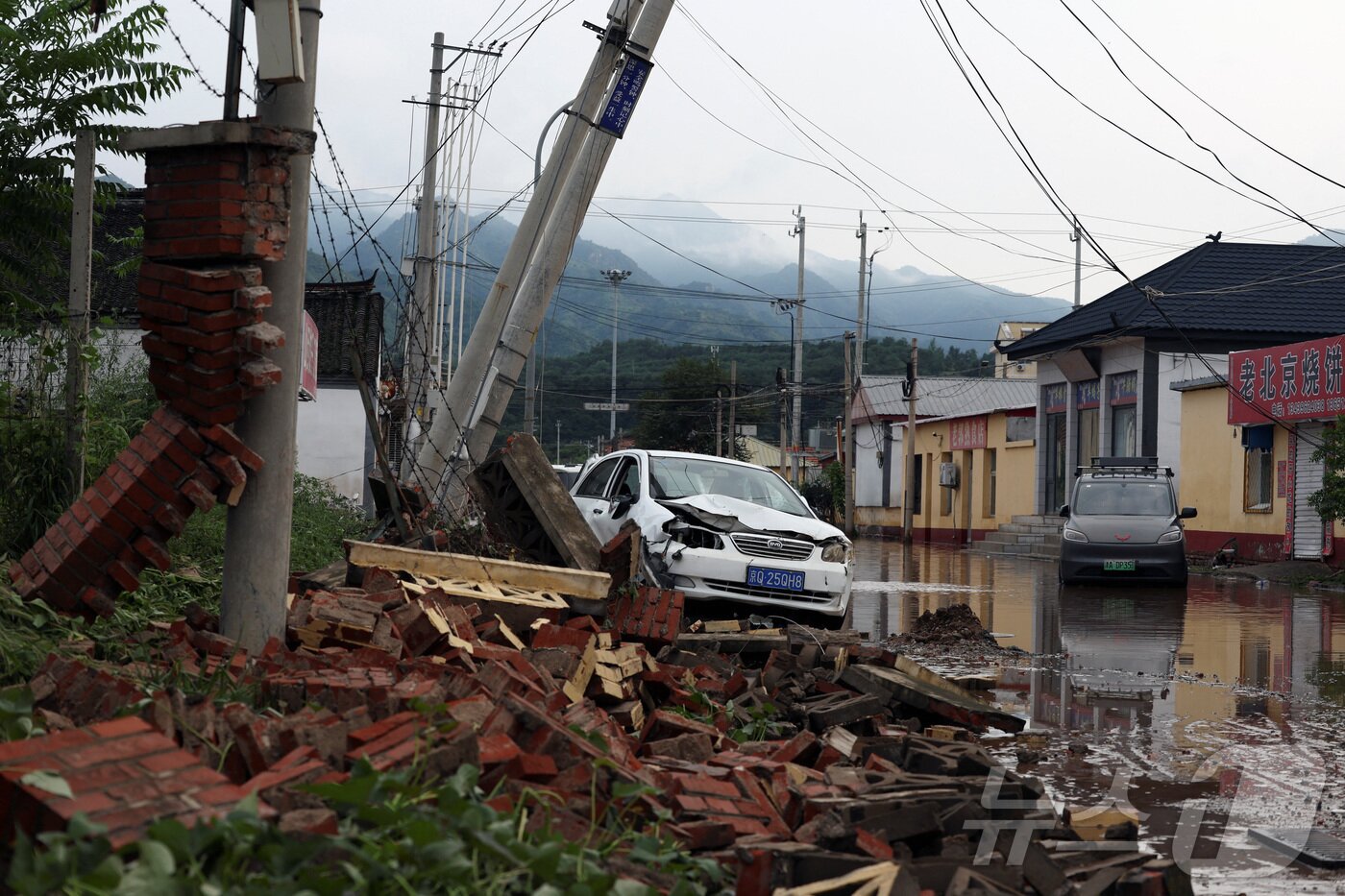 본문 이미지 - 중국 베이징 미윈구에서 폭우로 인해 지역이 침수되면서 파손된 차량과 잔해가 쌓여있다. 2025.7.28 ⓒ 로이터=뉴스1 ⓒ News1 정은지 특파원