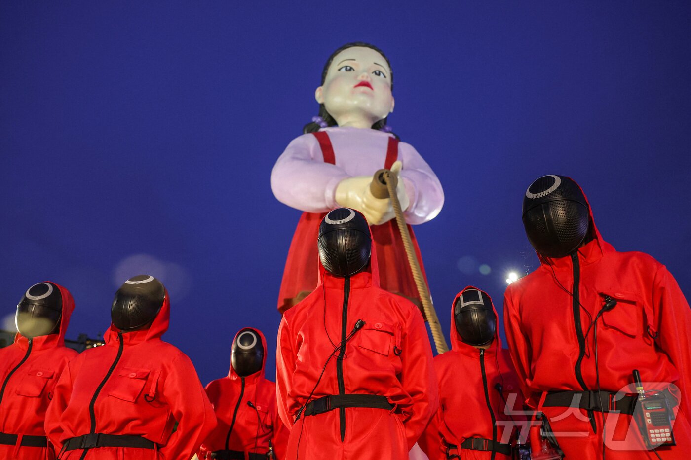 본문 이미지 - 지난 30일(현지시간) 태국 방콩 시청 광장에서 열린 '오징어 게임 3' 홍보 행사에서 핑크 복장의 진행요원들이 '영희' 인형과 함께 촬영을 하고 있다. ⓒ 로이터=뉴스1