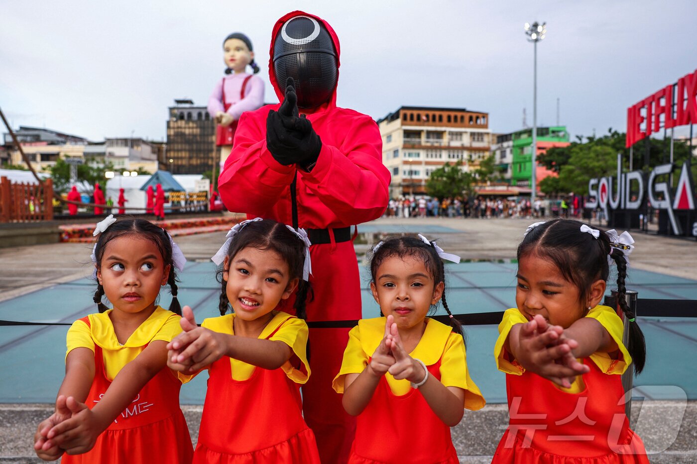 본문 이미지 - 지난 30일(현지시간) 태국 방콩 시청 광장에서 열린 '오징어 게임 3' 홍보 행사에서 어린이들이  오징어게임 진행요원 복장을 착용한 사람과 기념촬영을 하고 있다. ⓒ 로이터=뉴스1