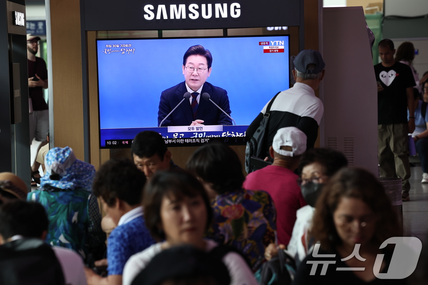 (서울=뉴스1) 구윤성 기자 = 3일 오전 서울역 대합실에서 시민들이 이재명 대통령 ‘취임 한달’ 기자회견 생중계 영상을 시청하고 있다. 2025.7.3/뉴스1