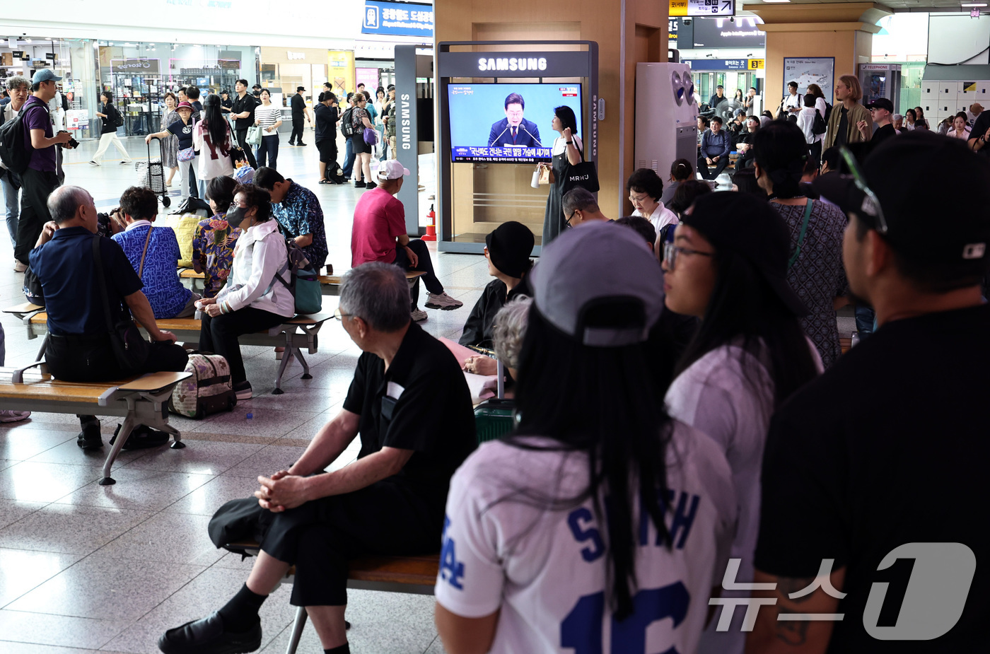 (서울=뉴스1) 구윤성 기자 = 3일 오전 서울역 대합실에서 시민들이 이재명 대통령 ‘취임 한달’ 기자회견 생중계 영상을 시청하고 있다. 2025.7.3/뉴스1