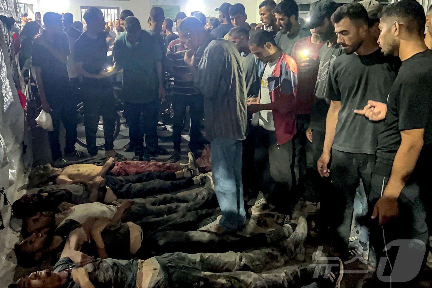 (가자시티 AFP=뉴스1) 윤다정 기자 = 30일(현지시간) 가자시티 알시파 병원에 검문소를 통과하는 구호 트럭을 기다리다 이스라엘군의 발포로 숨진 희생자들 곁에 팔레스타인 주민들 …