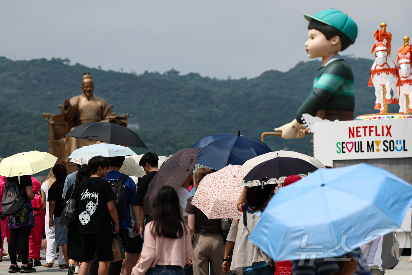 (서울=뉴스1) 김도우 기자 = 무더위가 이어진 4일 서울 종로구 광화문광장에 마련된 넷플릭스 오징어 게임 체험존에 관광객들이 양산을 쓰고 대기하고 있다. 2025.7.4/뉴스1