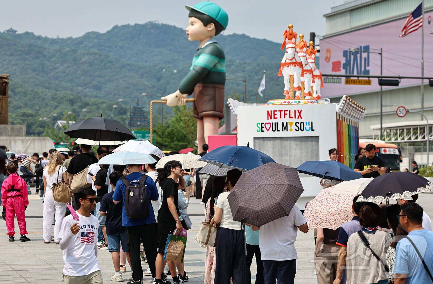 본문 이미지 - 무더위가 이어진 4일 서울 종로구 광화문광장에 마련된 넷플릭스 오징어 게임 체험존에 관광객들이 양산을 쓰고 대기하고 있다. 2025.7.4/뉴스1 ⓒ News1 김도우 기자