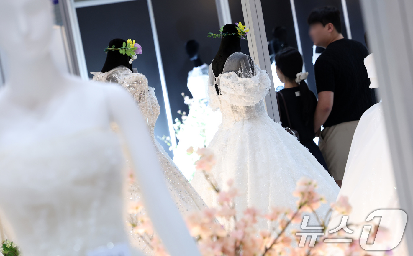 (서울=뉴스1) 김성진 기자 = 6일 서울 강남구 삼성동 코엑스에서 열린 2025 추계 웨덱스 웨딩 박람회에서 예비 부부들이 전시된 드레스를 살펴보고 있다. 2025.7.6/뉴스1 …